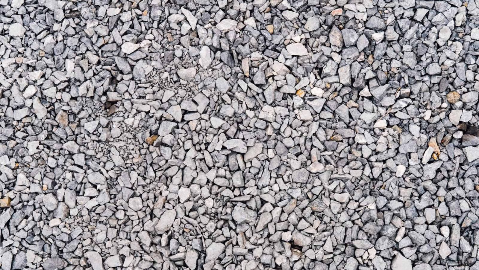 Nærbilde av grusdekke med mange små, kantete steiner i ulike gråtoner tett sammen.