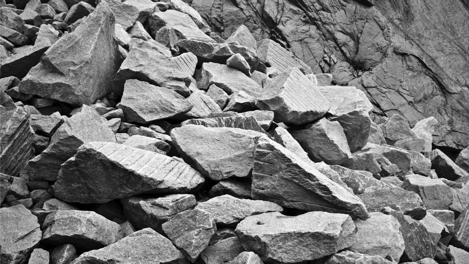 Haug med store, kantete steinblokker ved en fjellside, klare for bruk som bygge- eller fyllmasse.